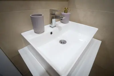 a white bathroom sink with two cups on it at Mips P86 Milmari Resort in Kopaonik