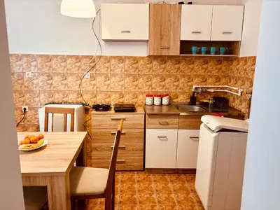 a small kitchen with white cabinets and a wooden table at Apartman Banjica 1 in Soko Banja