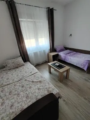 a bedroom with two beds and a table at Apartmani Ruj in Soko Banja