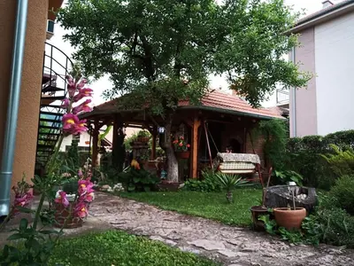 a garden with a pavilion with a bench and a tree at Apartman i Studio Stefan Nemanja Sokobanja in Soko Banja
