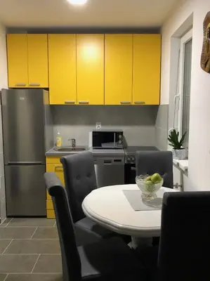 a kitchen with yellow cabinets and a table and chairs at Sunce in Kruševac