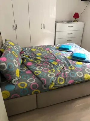 a bedroom with a bed with a colorful comforter and pillows at Sunce in Kruševac