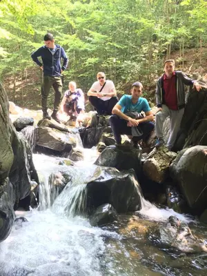 a group of people sitting on rocks by a stream at Domaćinstvo Trifunović in Pretrešnja