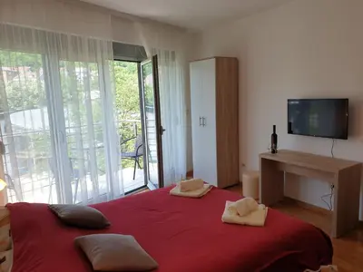 a bedroom with a large bed with red sheets and a television at Happy in Vrnjačka Banja