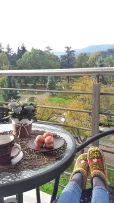 a person with their feet on a table on a balcony at Happy in Vrnjačka Banja