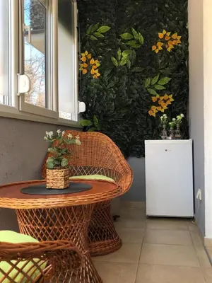 a wicker table and chair next to a wall with flowers at Apartman Radmanovac 2 in Vrnjačka Banja