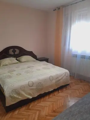 a bed in a bedroom with a wooden floor at Apartmani Arsic in Vrnjačka Banja