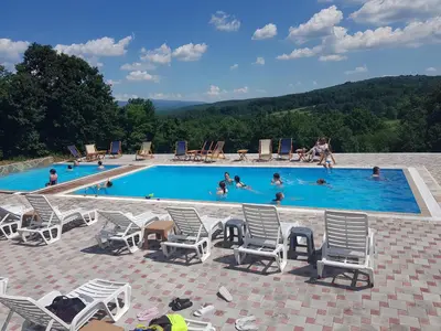 a large swimming pool with chairs and people in it at KONAK LJUBICA Rtanj in Boljevac