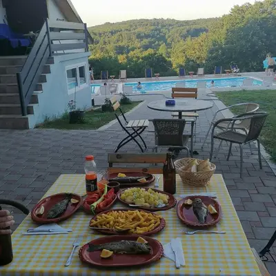 a table with plates of food on it with a pool at KONAK LJUBICA Rtanj in Boljevac