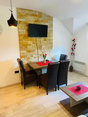 a dining room table with chairs and a tv on a brick wall at AM apartments in Kopaonik
