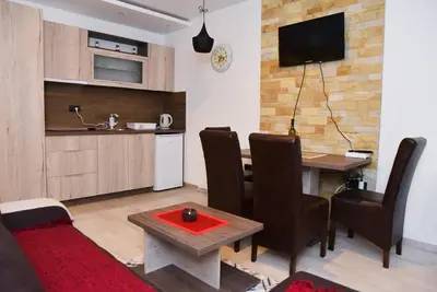 a living room with a table and a kitchen at AM apartments in Kopaonik