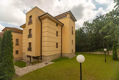 a large yellow building with a grass yard at Apartman Modena Lux in Vrnjačka Banja
