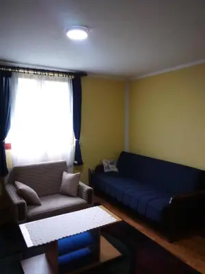 a living room with a blue couch and a window at Konak Mali Raj in Vrnjačka Banja