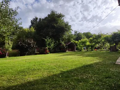 a large grassy yard with a house in the background at Konak Mali Raj in Vrnjačka Banja