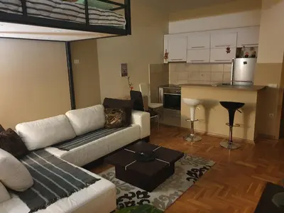 a living room with a couch and a kitchen at Stankovic apartman in Niš