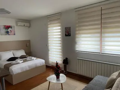 a bedroom with a bed and two windows with blinds at Imperia Apartments in Vrnjačka Banja