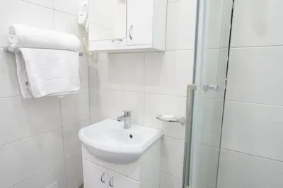 a white bathroom with a sink and a shower at Studio Simonovic in Vrnjačka Banja