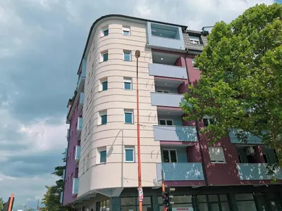 a tall white building with a tree in front of it at Cozy Corner Apartments - Free parking & Wi-fi in Ćuprija