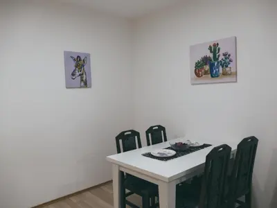 a dining room table with four chairs and two pictures on the wall at Cozy Corner Apartments - Free parking & Wi-fi in Ćuprija