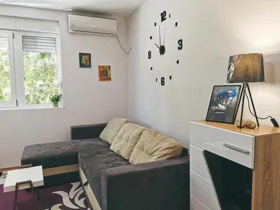 a living room with a couch and a clock on the wall at Cozy Corner Apartments - Free parking & Wi-fi in Ćuprija