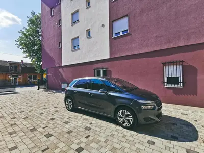 a black car parked next to a purple building at Cozy Corner Apartments - Free parking & Wi-fi in Ćuprija