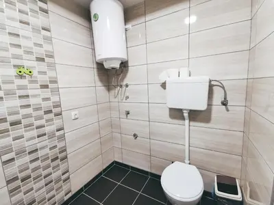 a bathroom with a white toilet and a wall at Cozy Corner Apartments - Free parking & Wi-fi in Ćuprija