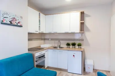 a small kitchen with white cabinets and a blue couch at Studio Borići in Soko Banja