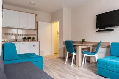 a living room with a dining room table and blue chairs at Studio Borići in Soko Banja