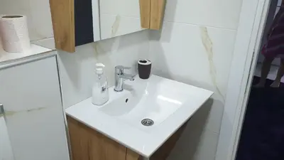 a bathroom sink with a soap dispenser on it at Apartman Sweet dreams 2 in Niš