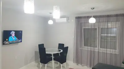 a living room with a table and chairs and a tv at Apartman Sweet dreams 2 in Niš