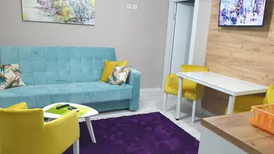 a living room with a blue couch and yellow chairs at Apartman Sweet Dreams 3 in Niš