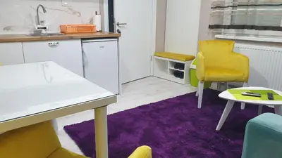 a kitchen with a table and a yellow chair and purple rug at Apartman Sweet Dreams 3 in Niš
