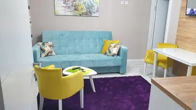 a living room with a blue couch and yellow chairs at Apartman Sweet Dreams 3 in Niš