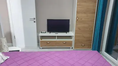 a bedroom with a tv on a dresser with a purple rug at Apartman Sweet Dreams 3 in Niš