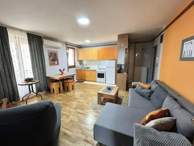 a living room with a blue couch and a kitchen at IDI MI - DODJI MI in Vrnjačka Banja