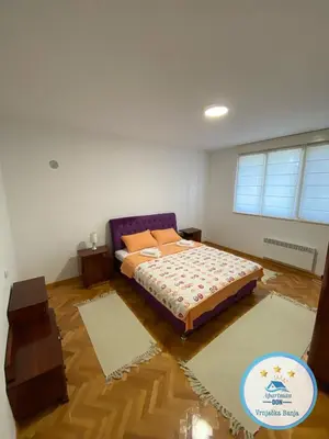 a bedroom with a bed and two rugs at Don in Vrnjačka Banja
