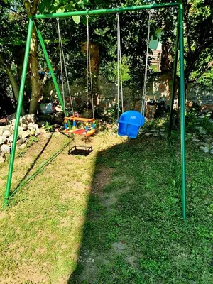 a swing set in the grass with a tree at Apartman Sergej 2 in Soko Banja