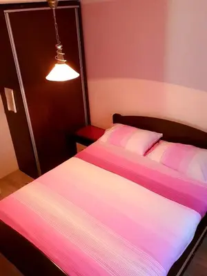 a bedroom with a bed with pink and white sheets at Apartman Sergej 2 in Soko Banja