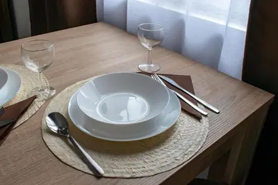 a table with a white plate and two wine glasses at Apartments Due Mondi in Vrnjačka Banja