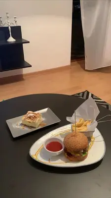 a plate with a hamburger and french fries on a table at Apartman Favorito 327 in Vrnjačka Banja