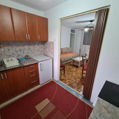 a kitchen with a refrigerator and a living room at Apartmani Sunčev breg Vlasinsko jezero in Surdulica