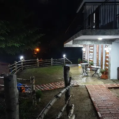 a night view of a house with a fence and a table at Apartmani Sunčev breg Vlasinsko jezero in Surdulica