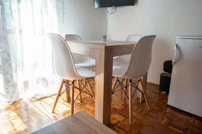 a group of white chairs around a wooden table at Apartmani Sunčev breg Vlasinsko jezero in Surdulica