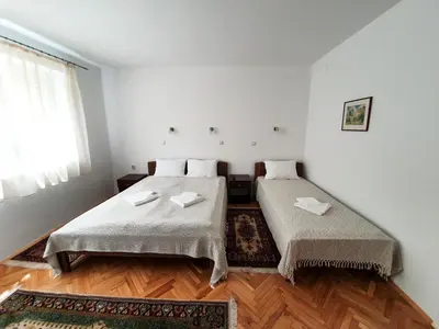 two beds in a room with white walls and wooden floors at Smestaj Katarina in Soko Banja