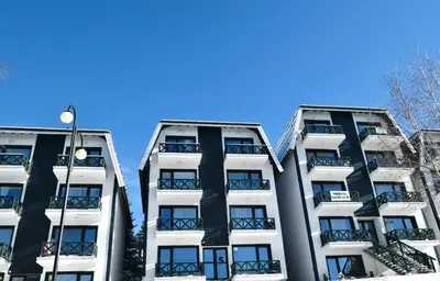 two tall white apartment buildings against a blue sky at Hiona Apartment in Kopaonik
