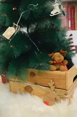a teddy bear sitting on a wooden box under a christmas tree at Hiona Apartment in Kopaonik
