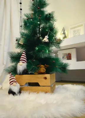 a christmas tree in a wooden box next to a rug at Hiona Apartment in Kopaonik