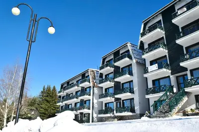 a building with snow in front of it at Hiona Apartment in Kopaonik