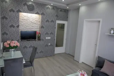 a living room with a couch and a television on a wall at DIS apartman 1 in Kruševac