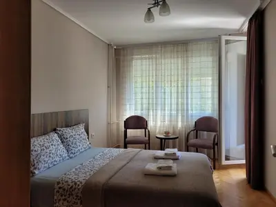 a bedroom with a bed and two chairs and a window at Duka Apartment in Niš